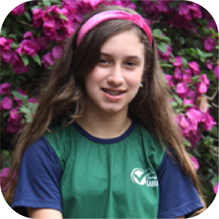 Foto de uma menina sorrindo para a captura da foto usando o uniforme do colégio UBM.