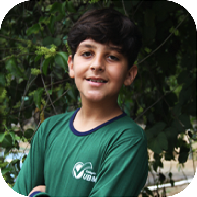 Foto de um menino sorrindo para a captura da foto usando o uniforme do colégio UBM.