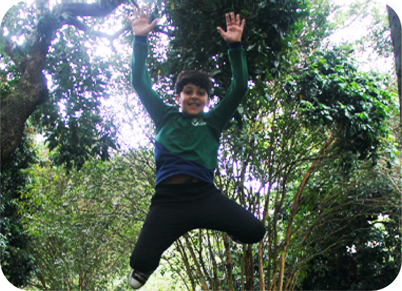 Foto de um menino sorridente no alto após um pulo com os braços para cima.